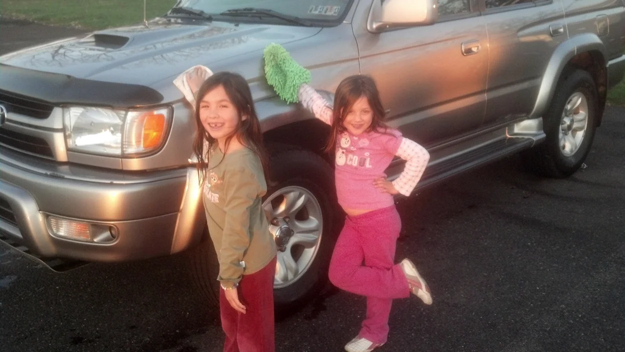 Two young girls helping to wash a family's silver Toyota 4Runner years ago